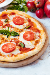 Classic Pizza with basil and tomato on top places on a bright background