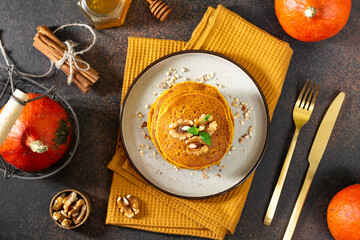 Pumpkin pancakes in a ceramic plate on a dark background top view