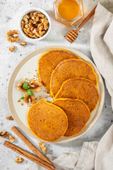 Pumpkin pancakes in a ceramic plate on a light gray culinary background with top view