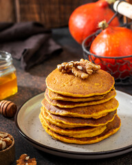 Pumpkin pancakes in a ceramic plate on a dark background close-up	