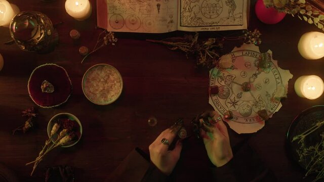 Witch cooking potion elixir top view. Table with spellbook for making rite. Herbs, burning candles, crystal magic ball for sacrifice. Halloween theme, full moon, witchcraft. 