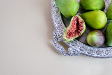 Juicy and ripe pear-shaped figs lie on a plate and cut against a light background.
