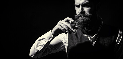 Attractive man with a whiskey. Handsome bearded man with stylish hair mustache and beard drinking...