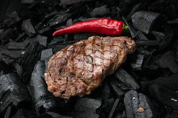 grilled steak on a background of black charcoal.

