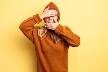 blonde pretty woman covering face with both hands saying no to the camera! refusing pictures or...