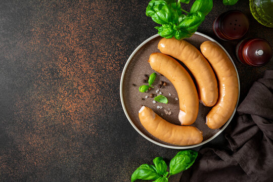 Pork sausages in a plate on a dark culinary background top view	