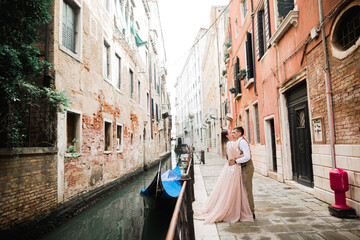 Fototapeta na wymiar Romantic, fairytale, happy newlywed couple hugging and kissing in Venice, Italy