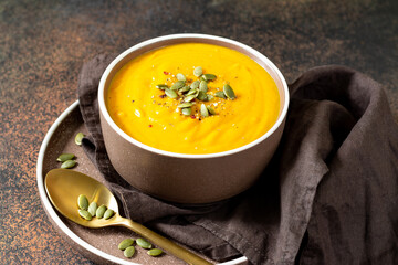 Pumpkin cream soup with seeds close-up on a dark background. Traditional autumn vegetarian dish on a dark background	
