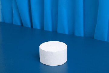 Podiums or pedestal Mock-up for cosmetic production on a blue background with folds of fabric.