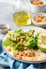 Hummus, chickpea and avocado salad on a plate, closeup view, selective focus