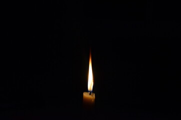 Luz amarilla de vela quem&aacute;ndose con un fondo negro.