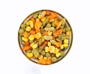 Salad of steamed vegetables cut into pieces on white background. It is composed of green beans, carrots and corn