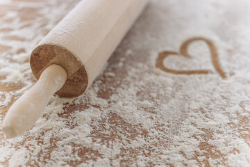 Sprinkled flour with heart painted on a wooden background, and rolling pin. Baking recipes. Valentine's day concept. Declaration of love