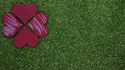 four red hearts on a green background