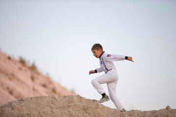 A young boy dressed as an American astronaut runs against the backdrop of the white mountains.