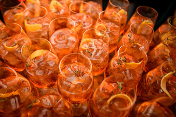 view of a lot of glasses of aperol spritz cocktail with ice cubes and orange slices