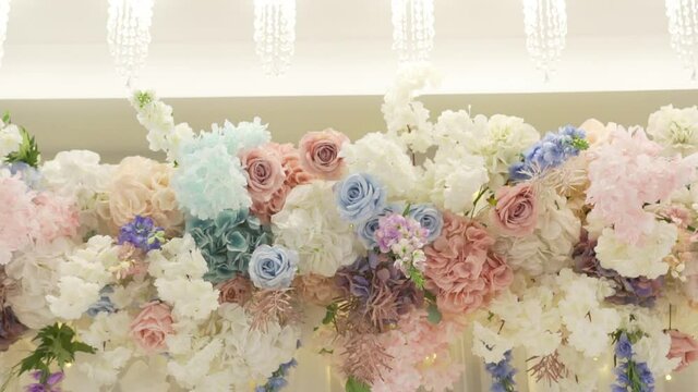 Flower arrangement is made by florist. Restaurant is decorated with bouquets of fresh flowers. Banquet hall with flower arrangements. Exquisite reception. Roses, hydrangeas, flowering cherry branches