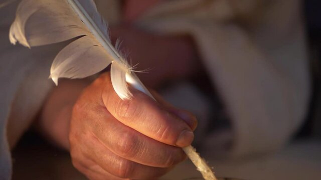 Dirty hands of peasant writing a letter with quill feather and ink 
