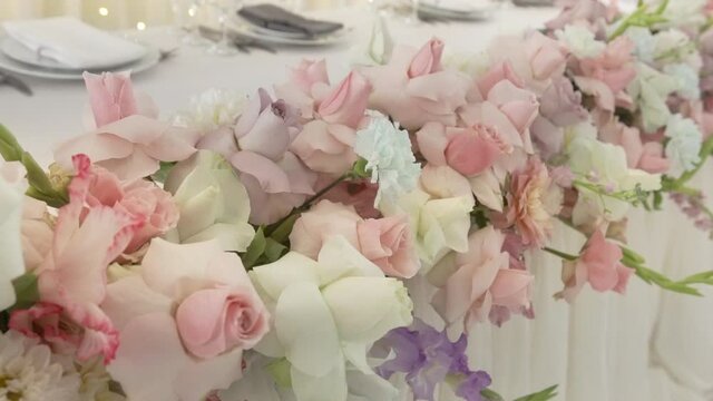 A floral arrangement of fresh flowers made by a florist decorates the holiday table. Roses, carnations, peonies, asters and gladiolus in a bouquet.