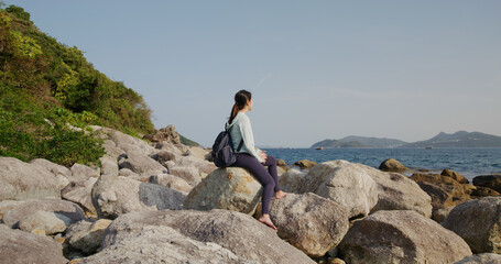 Obraz premium Woman sit on the rock and enjoy the sea view at beach
