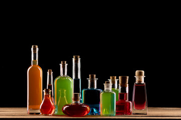 Colorful magic potions in glass bottles on wooden table. Magic and wizardry concept. Dark...