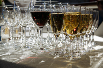in several rows glasses with drinks of white and red wine