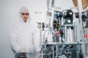 Scientists wearing protective clothing Inspect mask making machines in a laboratory at an industrial plant. Anti-virus production warehouse. concept of safety and prevention coronavirus covid-19.