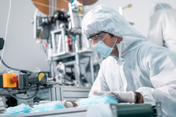 Naklejka premium Scientists wearing uniform protection. Check the manufacturing process of face masks. In a laboratory at industry plants. The concept for security and protection coronavirus covid-19.
