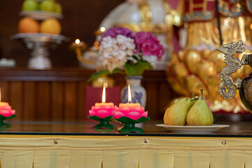 Closeup shot of a flower-shaped melted candle near the plates with fruits.