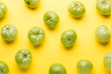 Green tomatoes for conservation on a yellow background. Unripe tomatoes for harvesting.