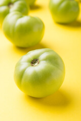 Green tomatoes for conservation on a yellow background. Unripe tomatoes for harvesting.
