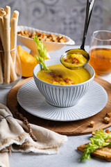 pumpkin cream soup, portion, restaurant serving, bread sticks and croutons, vertical format