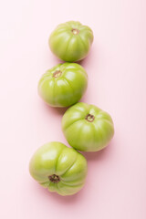 Green tomatoes for preservation on a pink background. Unripe tomatoes for harvesting.