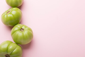 Green tomatoes for preservation on a pink background. Unripe tomatoes for harvesting.
