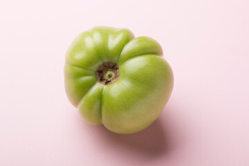 Green tomato for preservation on a pink background. Unripe tomatoes for harvesting.