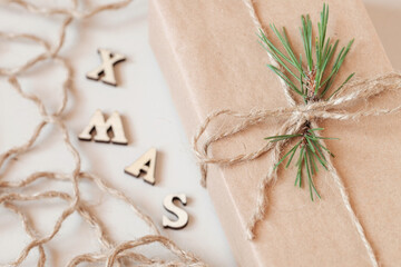 A Christmas gift wrapped in kraft paper and decorated with a pine twig. Xmas inscription