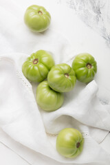 Green tomato for preservation on a white marble background. Unripe tomatoes for harvesting.