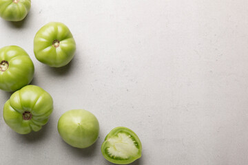 Green tomatoes for conservation on a gray background. Unripe tomatoes for harvesting. Cutaway tomato.