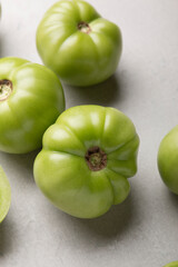 Green tomatoes for conservation on a gray background. Unripe tomatoes for harvesting. Cutaway tomato.