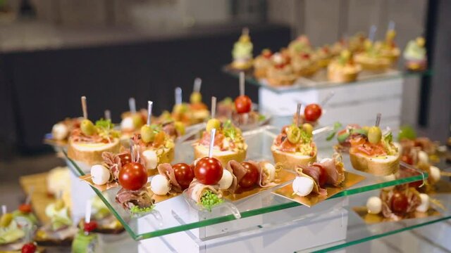 Gourmet delicious snacks. Canapes with organic products. Sandwiches with salmon and olives. Mozzarella cheese with cherry tomatoes and dried ham. Business banquet. Important event. Celebration