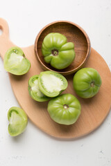 Green tomatoes for conservation on a wooden board on a gray background. Unripe tomatoes for harvesting. Cutaway tomato.