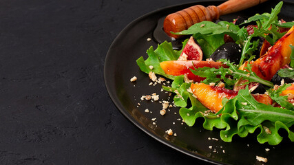 Fig salad with peach and fresh arugula leaves, honey dressing, on a black background, vegetarian, lifestyle, no people,