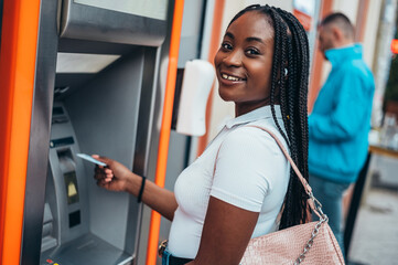 Beautiful african american woman using atm machine and a credit card
