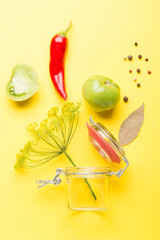 Green tomatoes for conservation with spices on a yellow background. Unripe tomatoes for harvesting. Pepper, garlic, allspice, cloves, horseradish, spices, bay leaf.