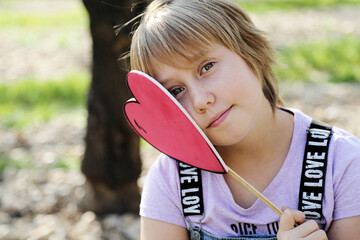 Outdoor portrait of 10 years old girl with heart - 458582190