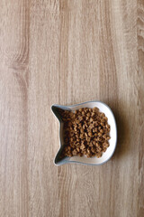 Cat shaped bowl filled with dry cat food. Top view.