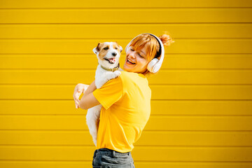 Pleased caucasian girl listening music with lovely jack russell terrier, plays and embraces four...