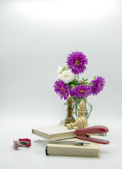 A composition of flowers in a vase, books and various educational accessories on a light background.