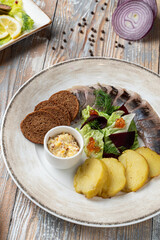 Salted herring with rye bread and baked potato,?garnished with greens and beetroot salad