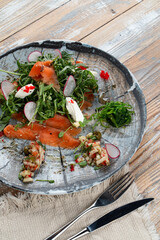 Smoked salmon and arugula salad with redish and scoops of cream cheese, close up